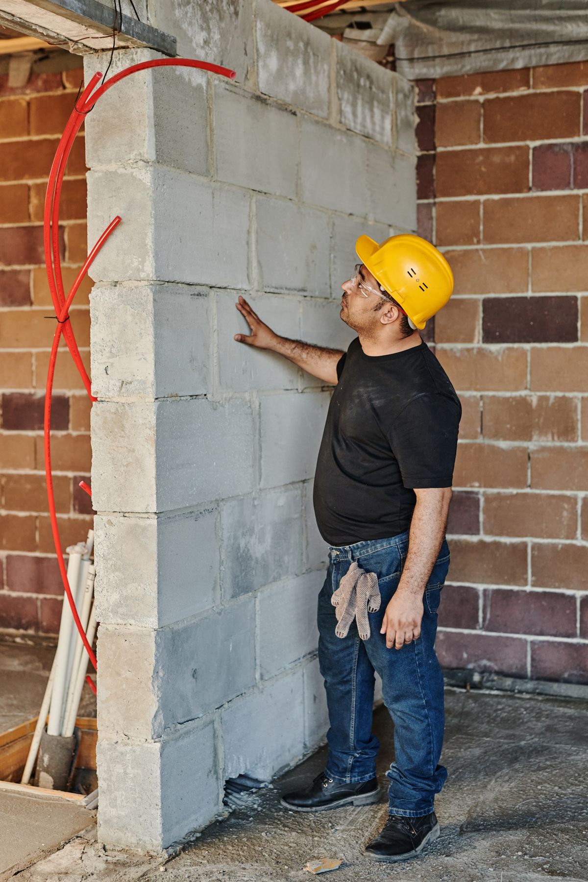 Illustrative stock photograph of a construction professional examining an interior masonry wall